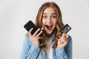 Młoda dziewczyna trzymająca kartę płatniczą i telefon