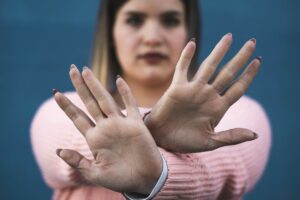 Młoda dziewczyna stoi ze skrzyżowanymi rękoma w geście protestu. Stop body shaming