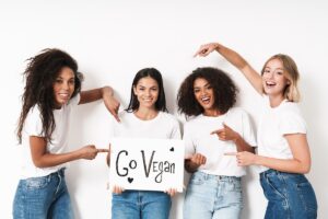 Młode dziewczyny trzymające tabliczkę z napisem "Go Vegan"